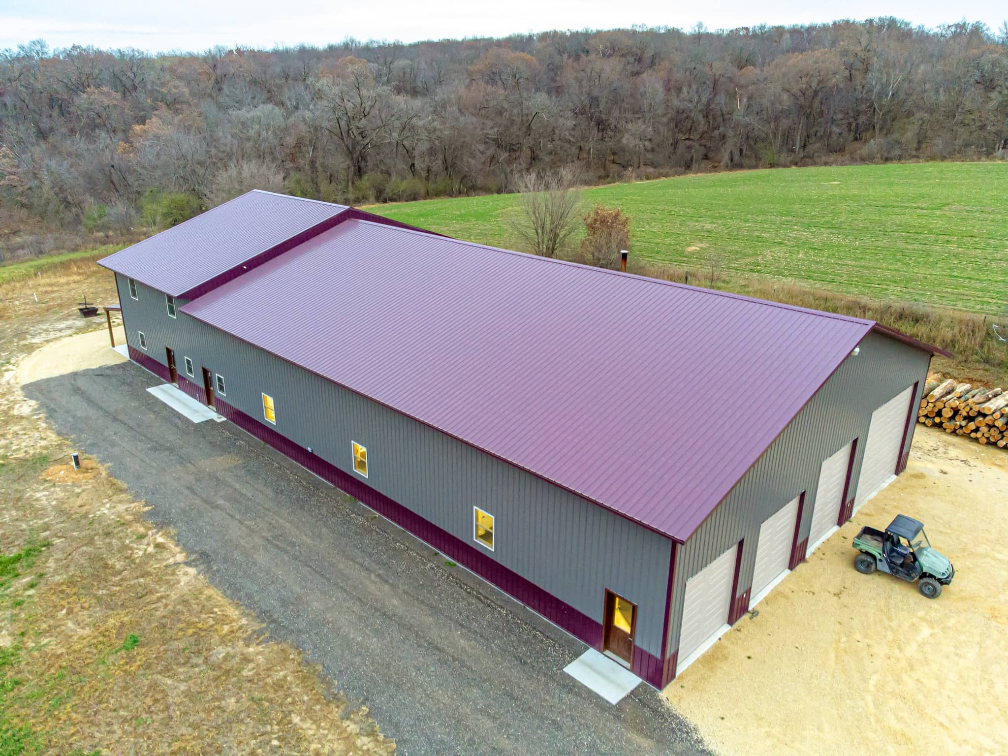 Steel post-frame shop building with a metal roof and overhead doors beside a farm field