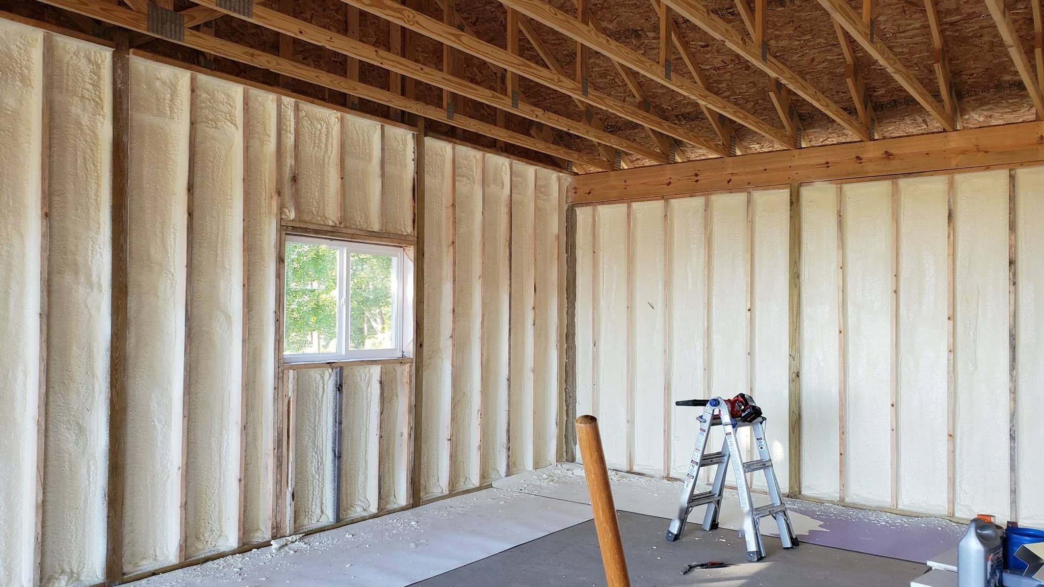 Garage interior with spray foam insulation on the stud walls and open roof trusses overhead