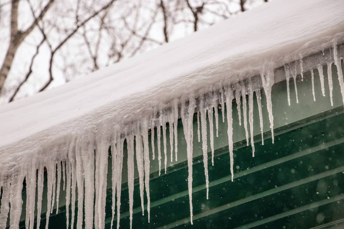 Thick icicles hanging from a snow-covered roof edge